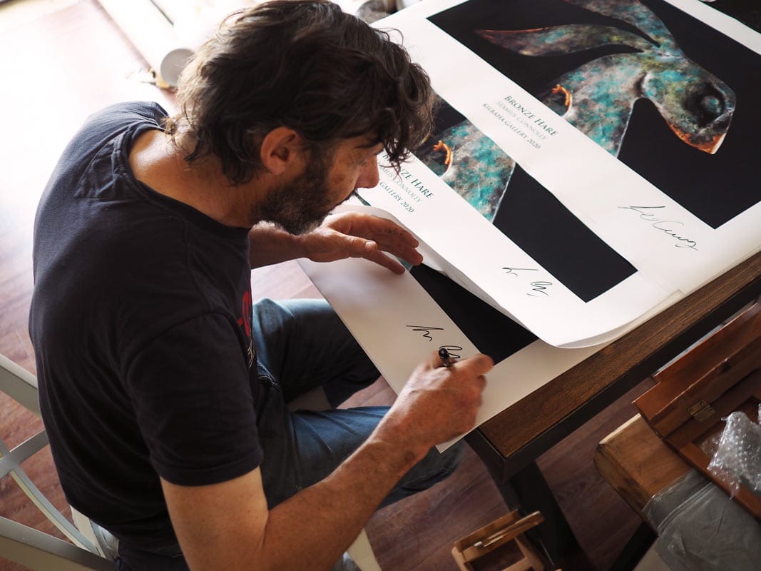 Artist Seamus Connolly signing posters of his work Kilbaha Gallery